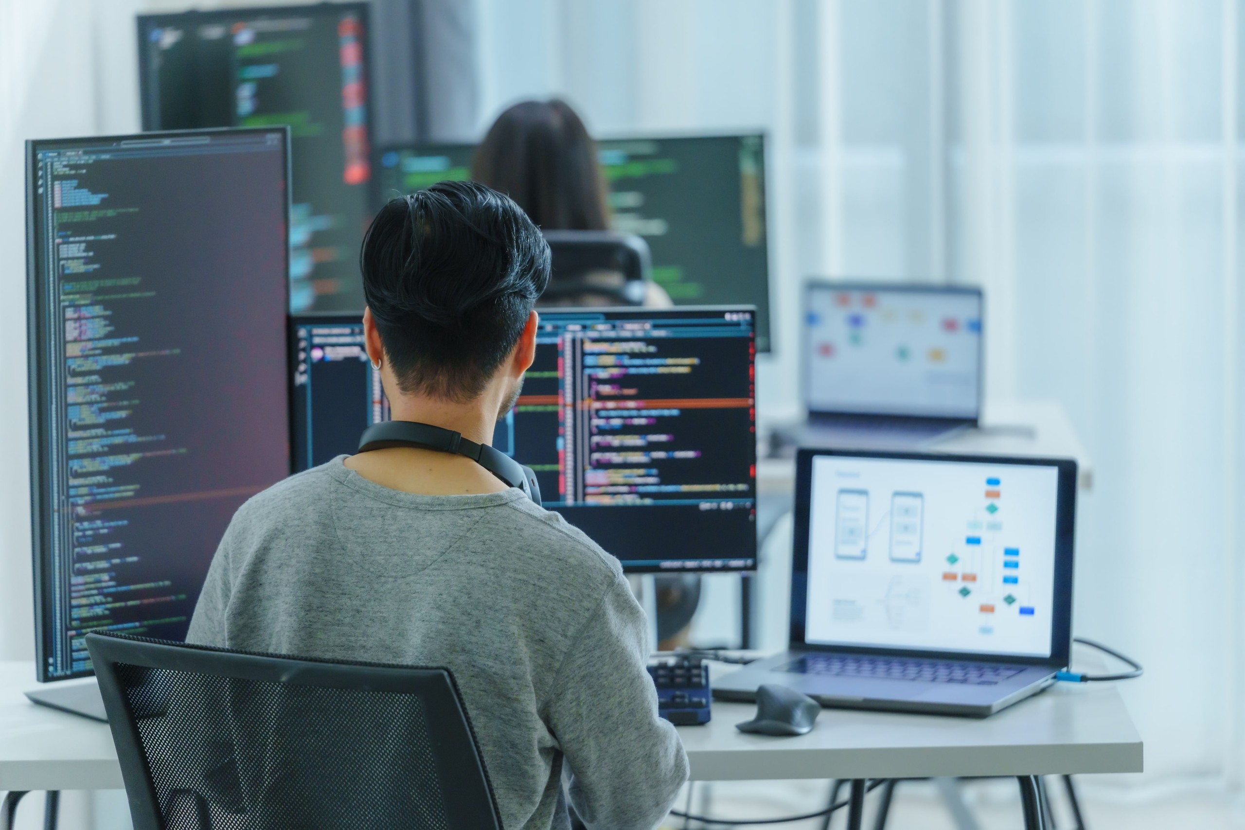 Person sitting at desk with multiple monitors