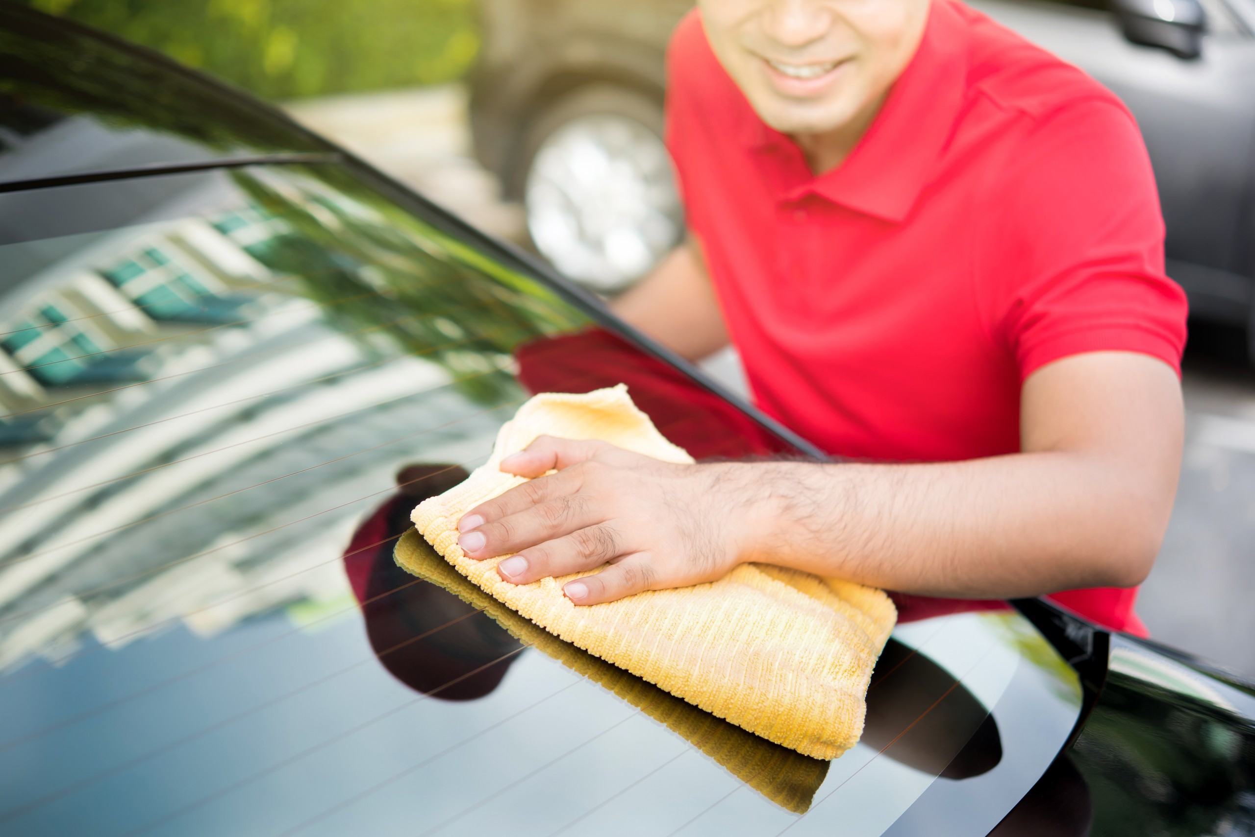 A person cleaning a vehicle's windshield.