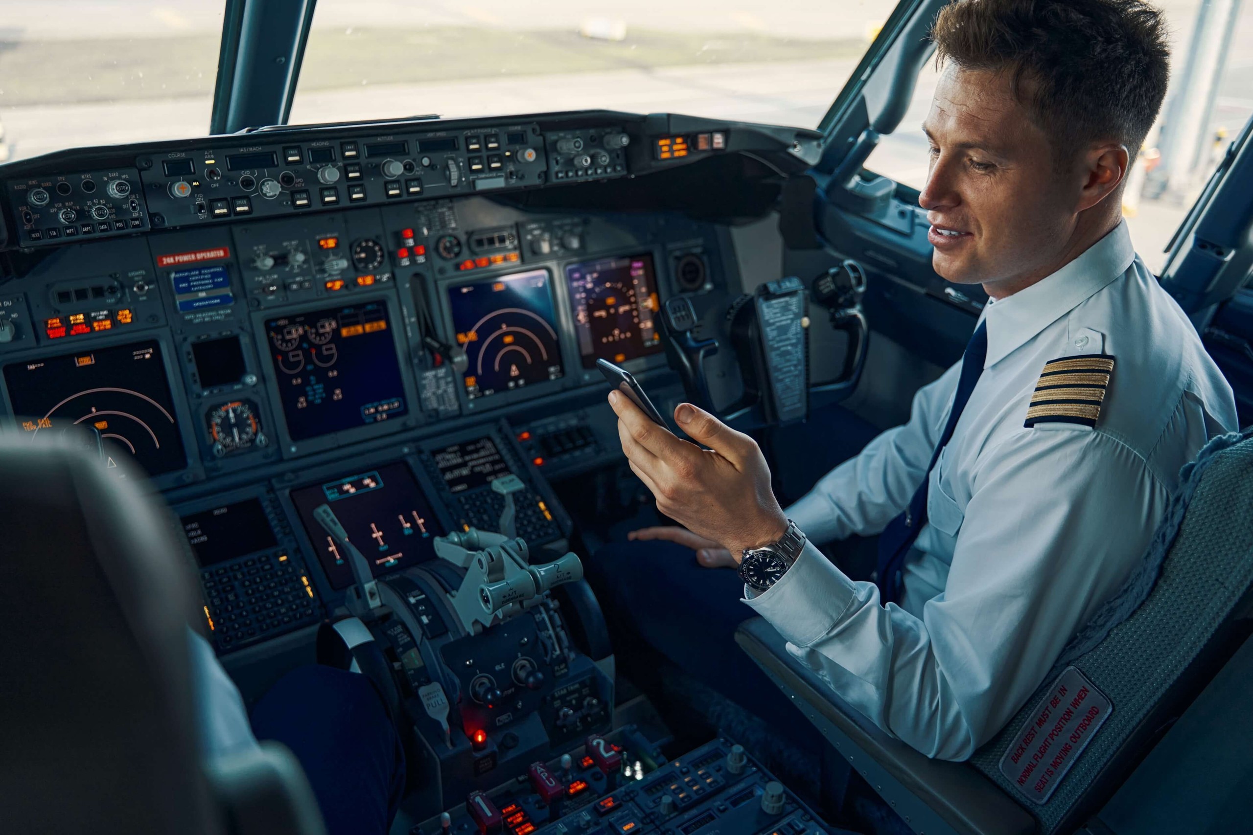 pilot looking at phone in cockpit of aircraft